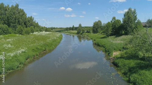 Aerial view summer landscape, river among trees. countryside, the banks of the river are covered with greenery, against the sky and clouds.