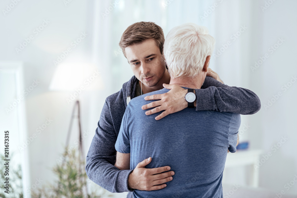 Foto de Sincere support. Sad man hugging senior man and looking down do  Stock | Adobe Stock