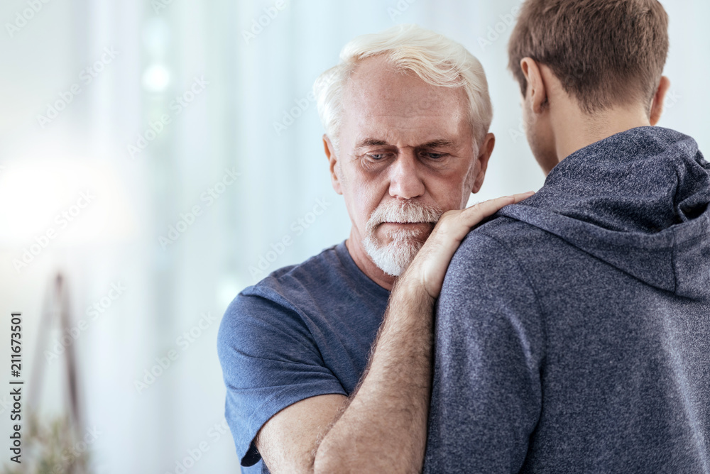 Not alone. Handsome senior man staring down and hugging man Not alone. Handsome senior man staring down and hugging man