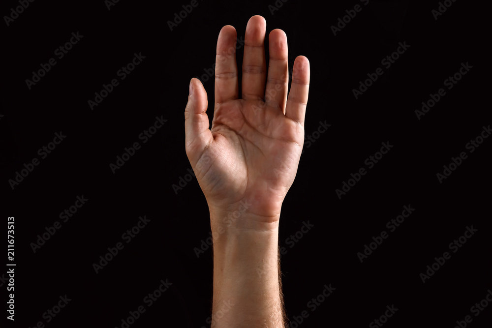 Male palm raised up, isolated on a dark background. Isolate Male palm raised up, isolated on a dark background. Isolate