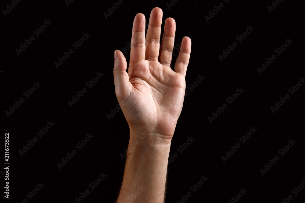 Male palm raised up, isolated on a dark background. Isolate