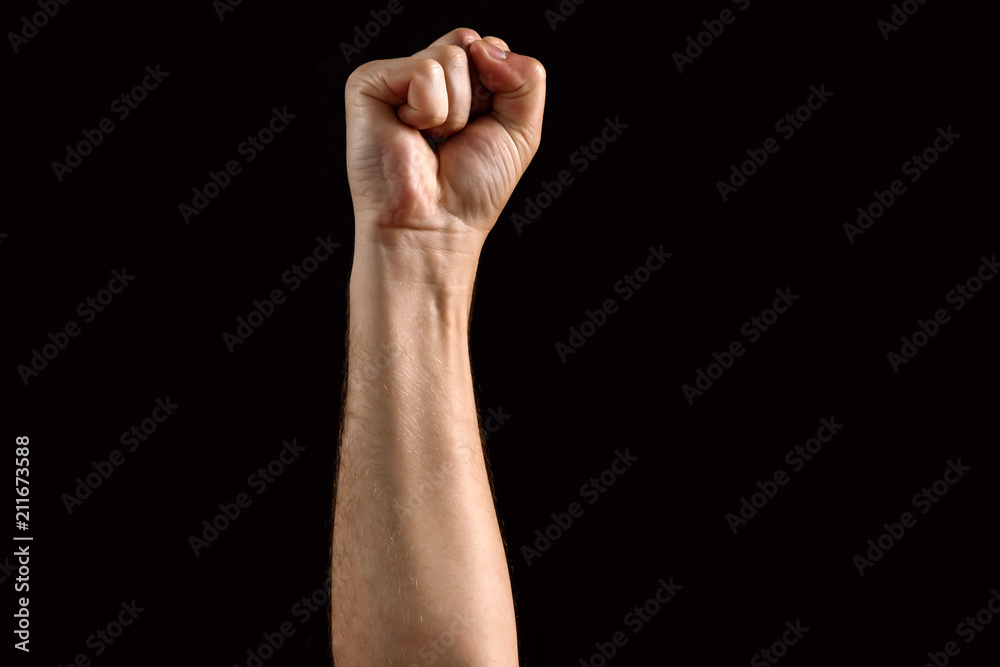 Male fist raised up, isolated on a dark background. Isolate Male fist raised up, isolated on a dark background. Isolate