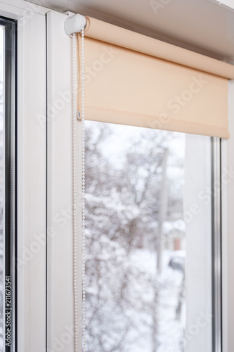 Beige blackout roller blind on the white plastic window. Shutters on the plastic window.