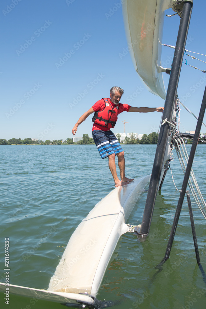 Fototapeta premium salior trying to right his catamaran after capsize