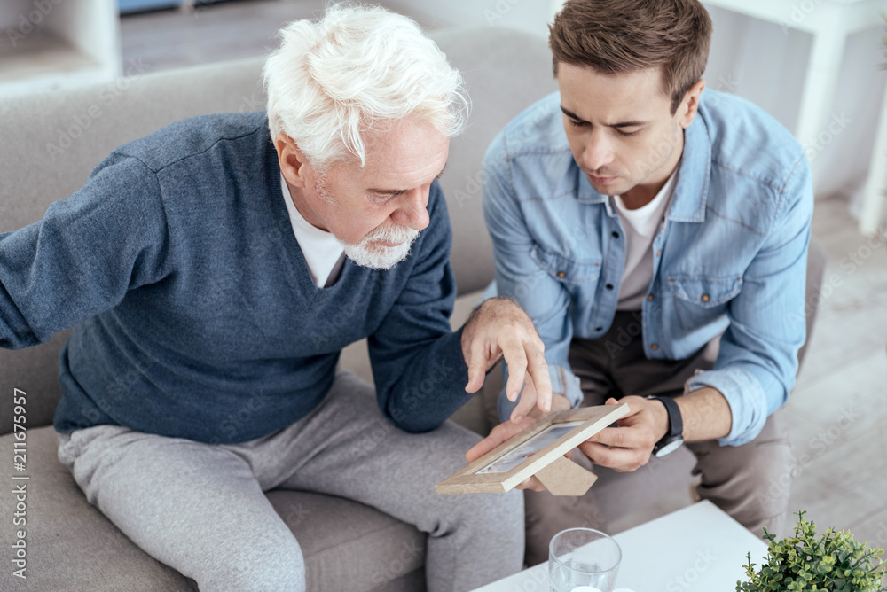 Obraz premium Who is it. Appealing senior man asking questions and man holding photo