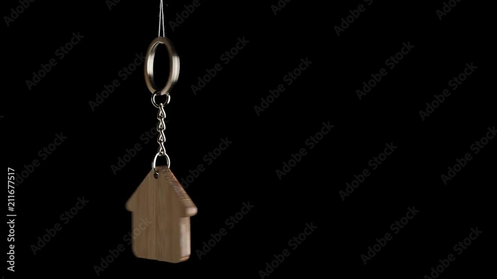 Wooden key holder with house shape hanging and rotating on black background Wooden key holder with house shape hanging and rotating on black background