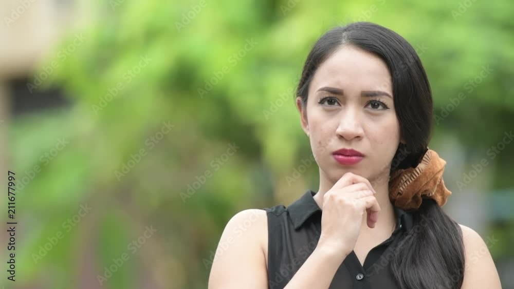 Young beautiful Asian businesswoman thinking in the streets outdoors