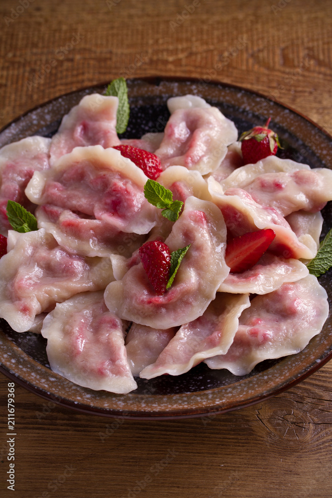 Dumplings, filled with strawberries, berries. Pierogi, varenyky, vareniki, pyrohy - dumplings with filling, popular dish in many countries. vertical