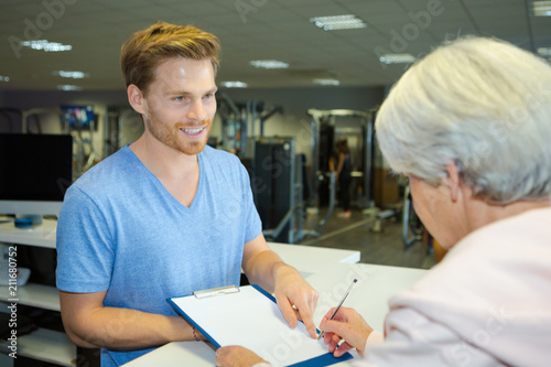 fitness trainer offering pen to sign up gym contract