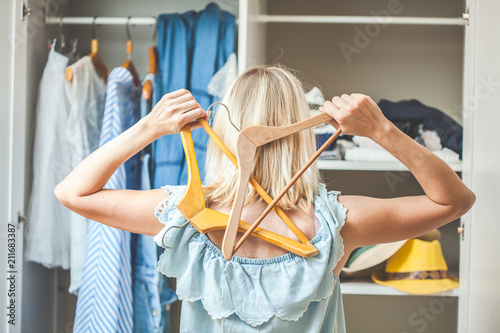 girl near a wardrobe with clothes can not choose what to wear. Heavy Choice Concept has nothing to wear