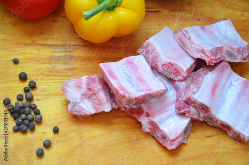Raw uncooked pork ribs on a paper on dark brown wooden background. Ingredients for meat raw pork ribs sage, thyme, rosemary, pepper, basil, salt. photo