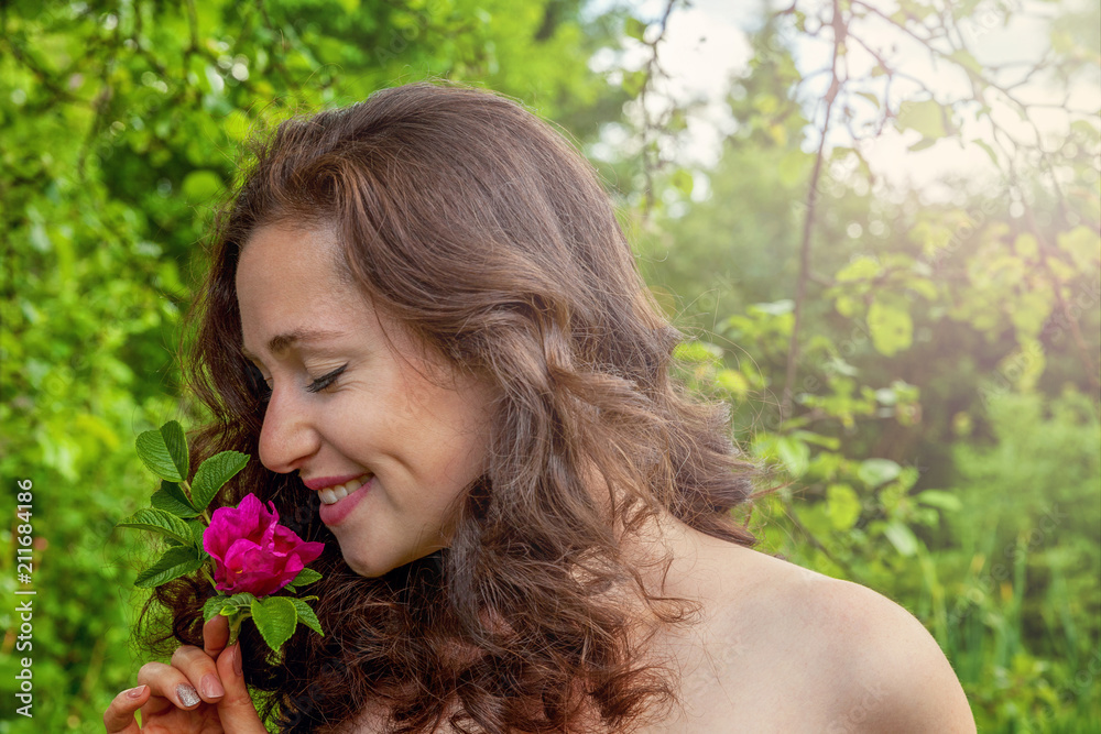 Beautiful young brunette girl with perfect skin holding red rose flower in hand on park or garden green background. Beauty nature skincare eco organic cosmetic ecology pure health concept Beautiful young brunette girl with perfect skin holding red rose flower in hand on park or garden green background. Beauty nature skincare eco organic cosmetic ecology pure health concept