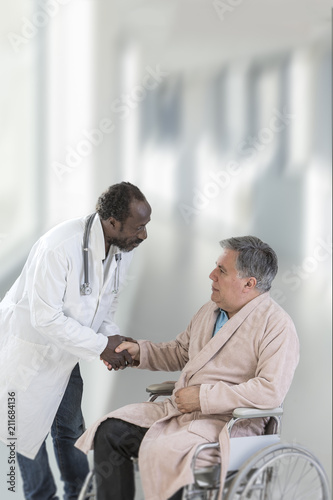 African ,American,male doctor greeting recovering senior patient in wheelchair in hospital handshake © JPC-PROD