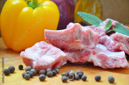 Raw uncooked pork ribs on a paper on dark brown wooden background. Ingredients for meat raw pork ribs sage, thyme, rosemary, pepper, basil, salt. photo
