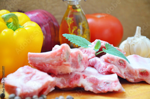 Raw uncooked pork ribs on a paper on dark brown wooden background. Ingredients for meat raw pork ribs sage, thyme, rosemary, pepper, basil, salt. photo