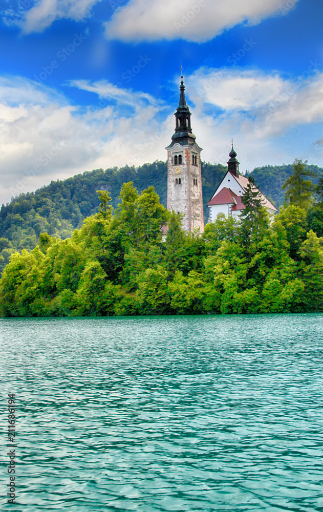 Lake Bled with castle and church on the island is in Slovenia in Europe. There is turqoise water and blue sky.  