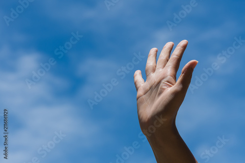 Woman raise hand up showing the five fingers on blue sky with white cloud background