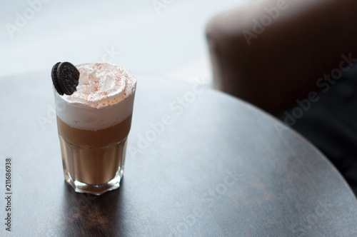 Milkshake macchiato overshake with chocolate and cookies. Cappuccino with whipped creamand caramel on a wooden table in a coffee house. Trendy food concept. photo