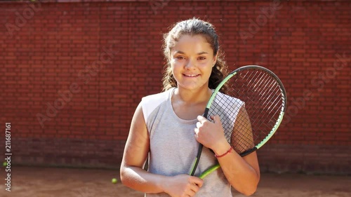 Portrait of pretty young tennis playgirl with racket smiling and going at camera photo