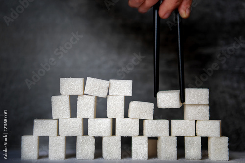 Photography Financial pyramid: a man builds an unstable tower of pieces of sugar