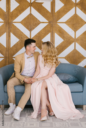 Beautiful loving young couple at home in a beautiful interior and elegant outfits look at each other