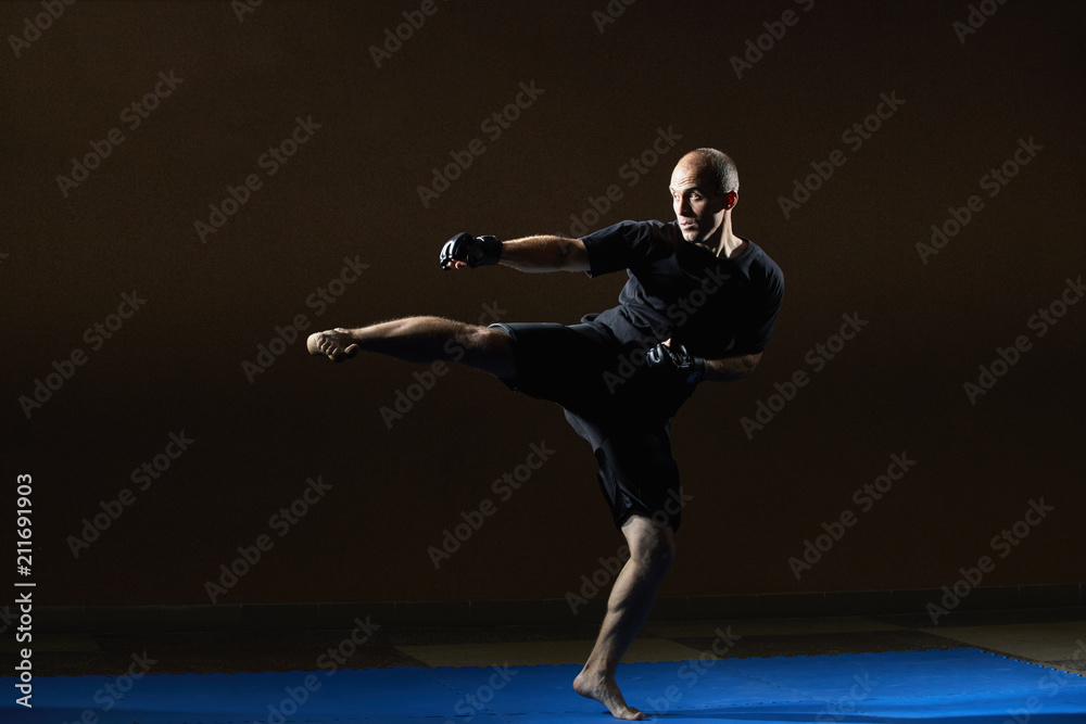 A man in black gloves beats his kick to the side