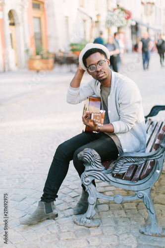 young african college student playing guitar outdoors