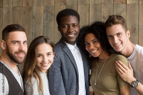 Portrait of happy multiracial people smiling at camera showing racial unity and equality, diverse millennial students being united posing for picture, laughing and having good time together.