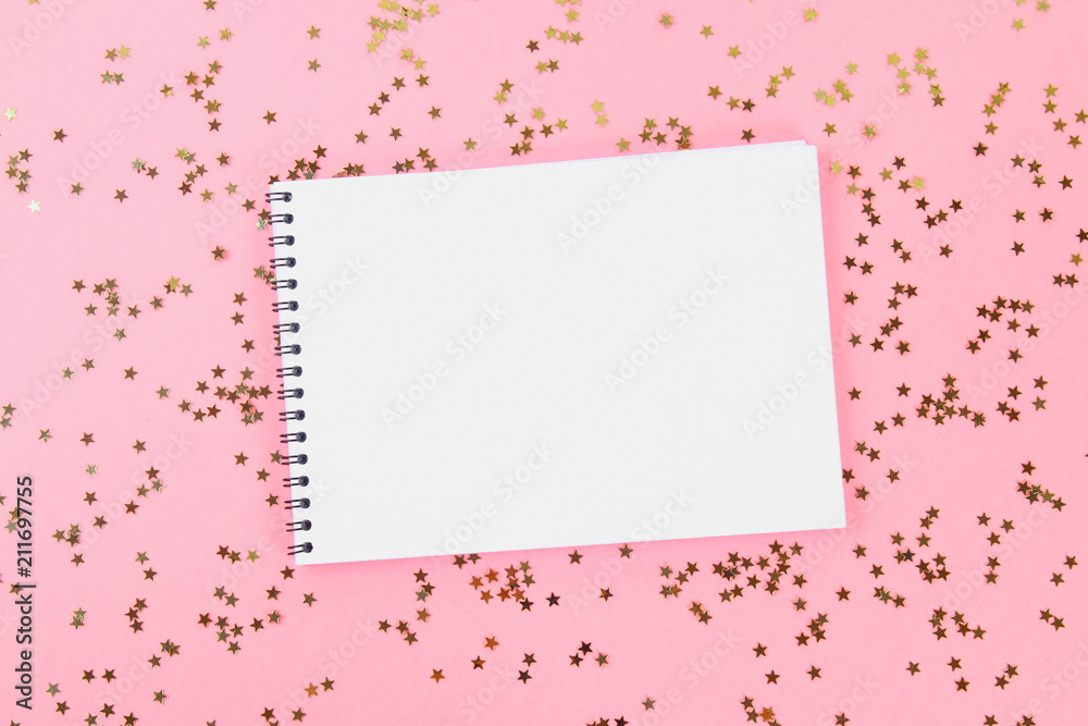 An empty pad on a pastel background surrounded by shiny decorative stars and balls.