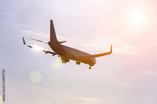 Passenger plane flying in the blue sky in sunlight rays photo