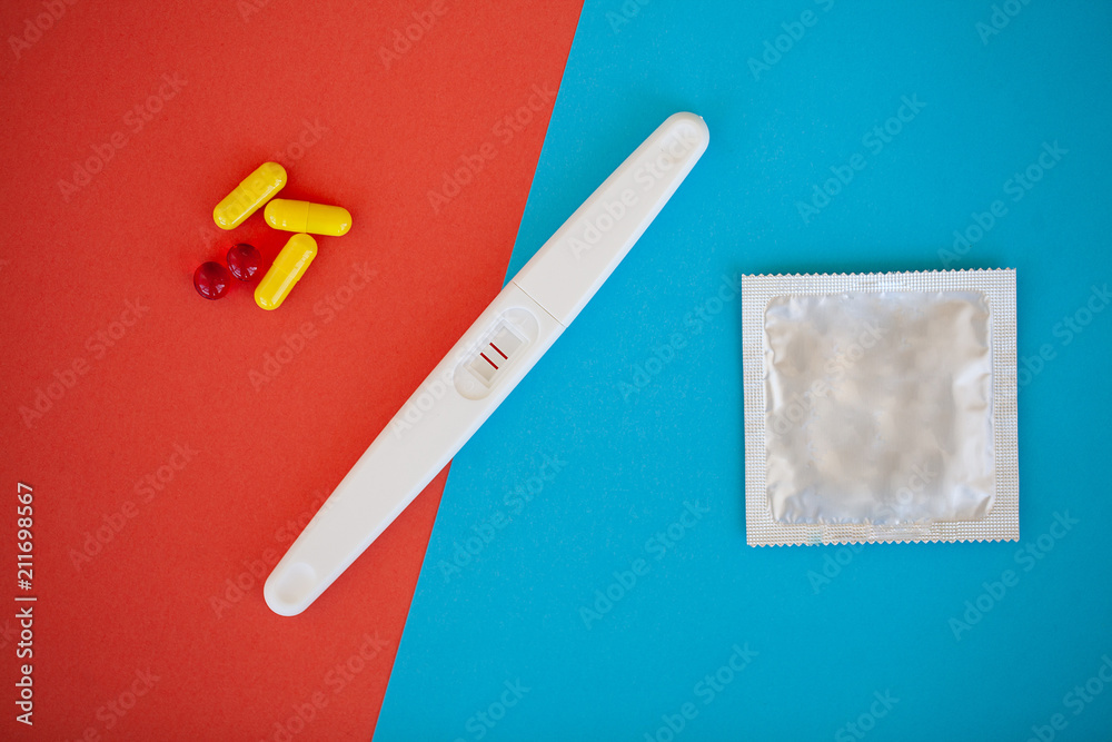 Pregnancy test. The result is positive with two strips and condom with contraceptive on colored background, Birth control pill, safe sex, healthcare concep Pregnancy test. The result is positive with two strips and condom with contraceptive on colored background, Birth control pill, safe sex, healthcare concep