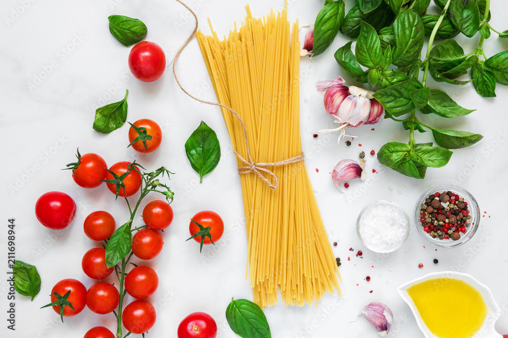 raw pasta spaghetti with tomatoes, garlic and basil on white marble background. cooking concept. top view raw pasta spaghetti with tomatoes, garlic and basil on white marble background. cooking concept. top view