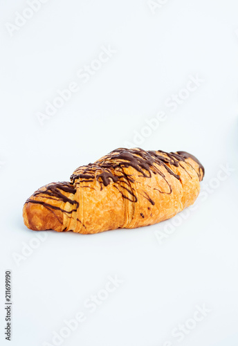 Fresh croissant poured with chocolate isolated on white background