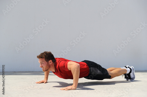 Pushup fitness man doing push-up bodyweight exercise on gym floor. Athlete working out chest muscles strength training outdoors