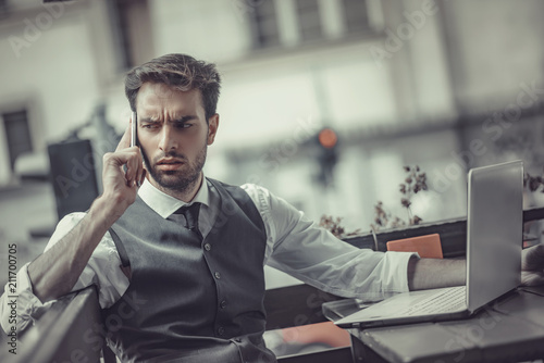 Worried young entrepreneur receiving worrying and bad news over his cell phone