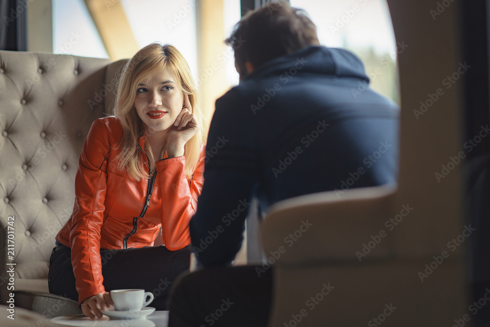 Young woman and man on a first date, man flirting and seducing a gorgeous blonde woman, man from the back, unrecognizable face Young woman and man on a first date, man flirting and seducing a gorgeous blonde woman, man from the back, unrecognizable face