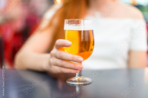 Young redhead pretty girl enjoying a beer at a mall