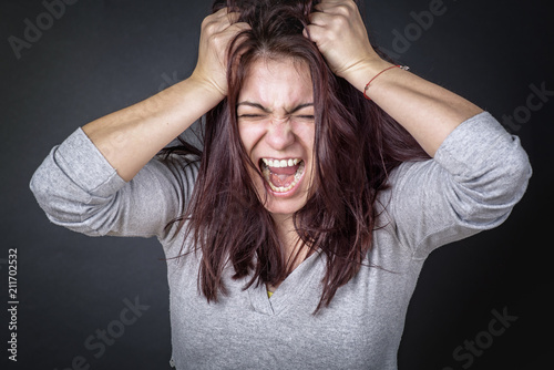 Frustrated angry woman screaming and pulling her hair, young woman angry photo