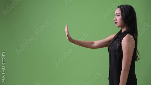 Profile view of young beautiful Asian businesswoman with stop gesture