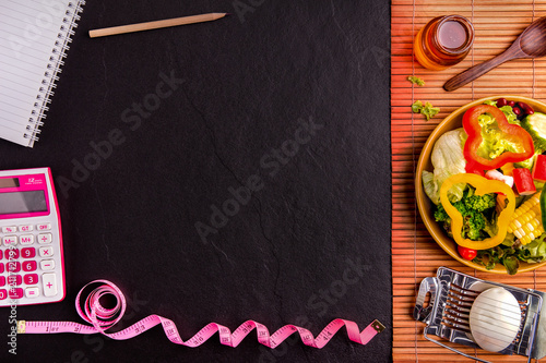 Diet plan, tape measure, calculator for Count calories,  .salad healthy food on wood and black stone background.Weight loss. Copy space.