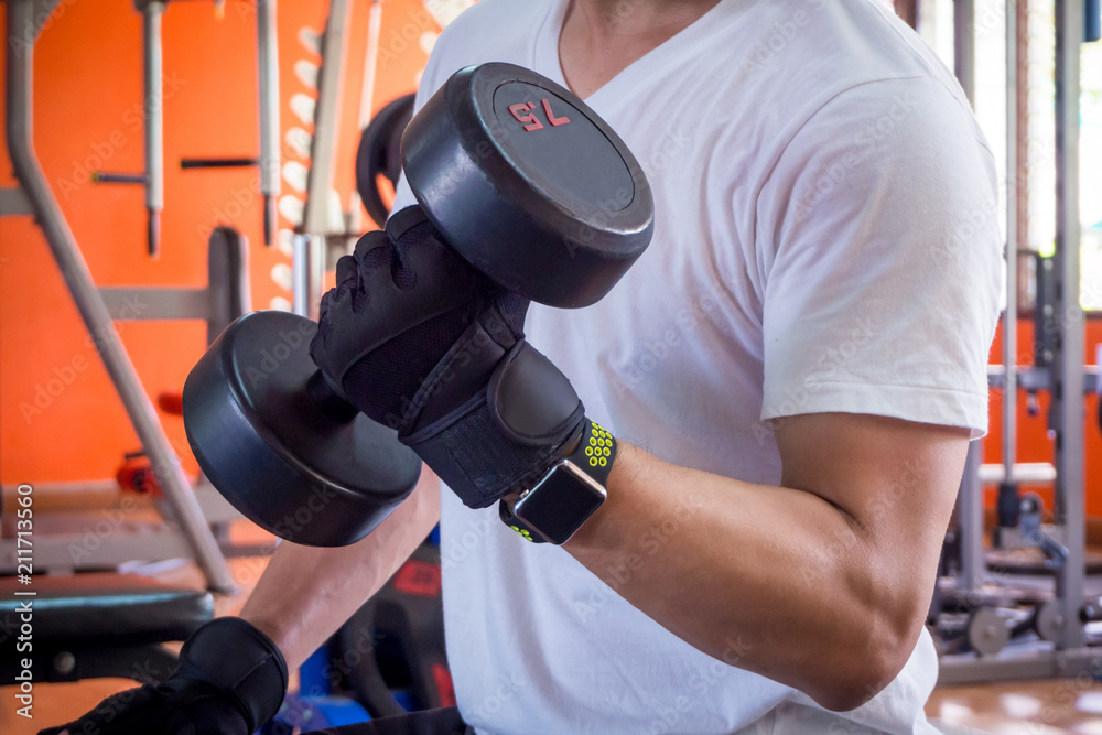 Arm of a man lifting up dumbell in gym Arm of a man lifting up dumbell in gym
