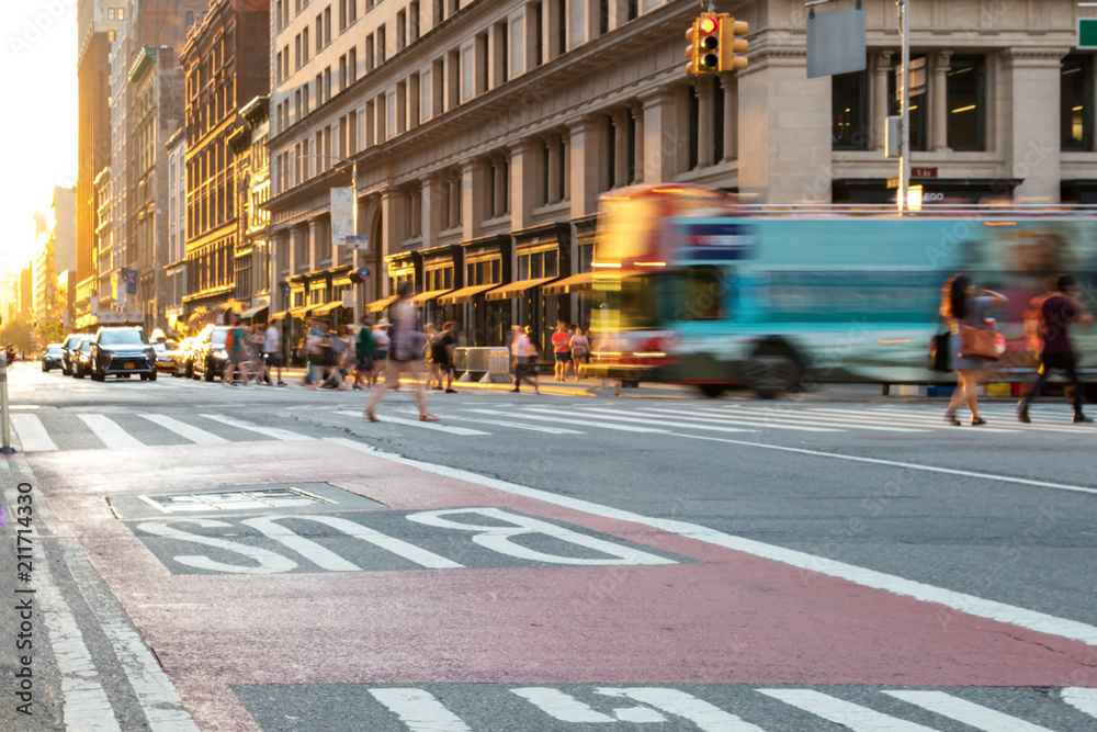 Obraz premium Nowy Jork autobus turystyczny jadący w dół 5th Avenue na Manhattanie z ludźmi przechodzącymi przez skrzyżowanie i zachód słońca w tle