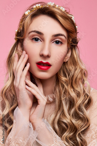 Fashion photo of young woman on pink background wearing gold diadem
