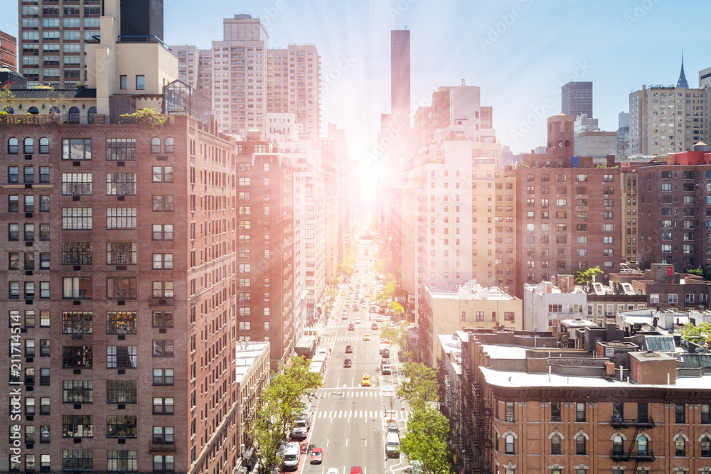 Naklejka premium Zasięrzutny widok First Avenue w Manhattan Nowy Jork z jaskrawym światłem słonecznym w tle