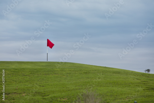 red flag on golf course on green hill marking 18th hole