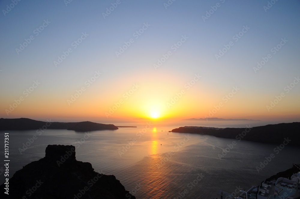 Sunset view with white architectures and colorful houses above the volcanic caldera in the village of Thira in Santorini island, Greece Sunset view with white architectures and colorful houses above the volcanic caldera in the village of Thira in Santorini island, Greece