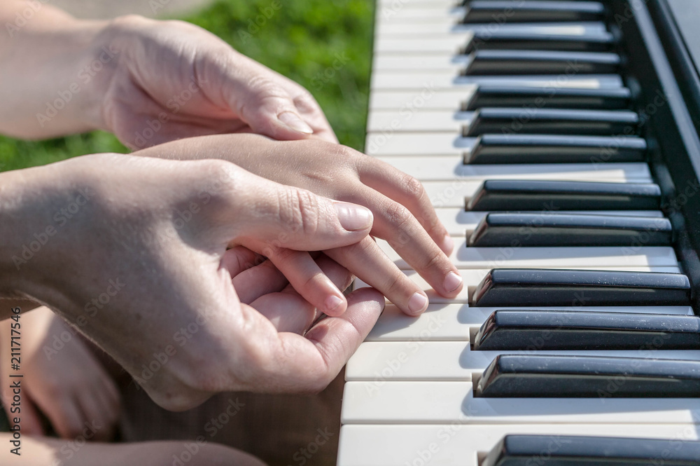 Mother teaches the daughter to play the piano. Concept Mother's Day. Female and children's hands. Mother teaches the daughter to play the piano. Concept Mother's Day. Female and children's hands.
