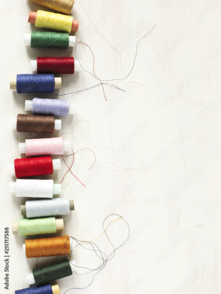 Colourful thread spools on a white wooden background with copy space Colourful thread spools on a white wooden background with copy space