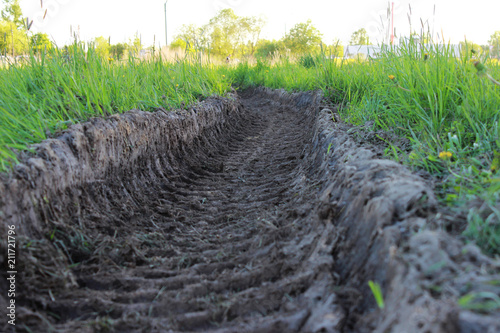 traces of heavy machinery tractor in the sand on the summer lush green grass. photo