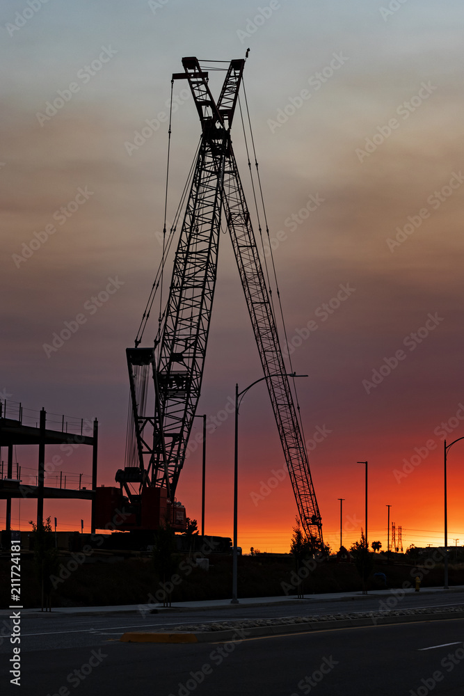 Construction crane at job site during sunset